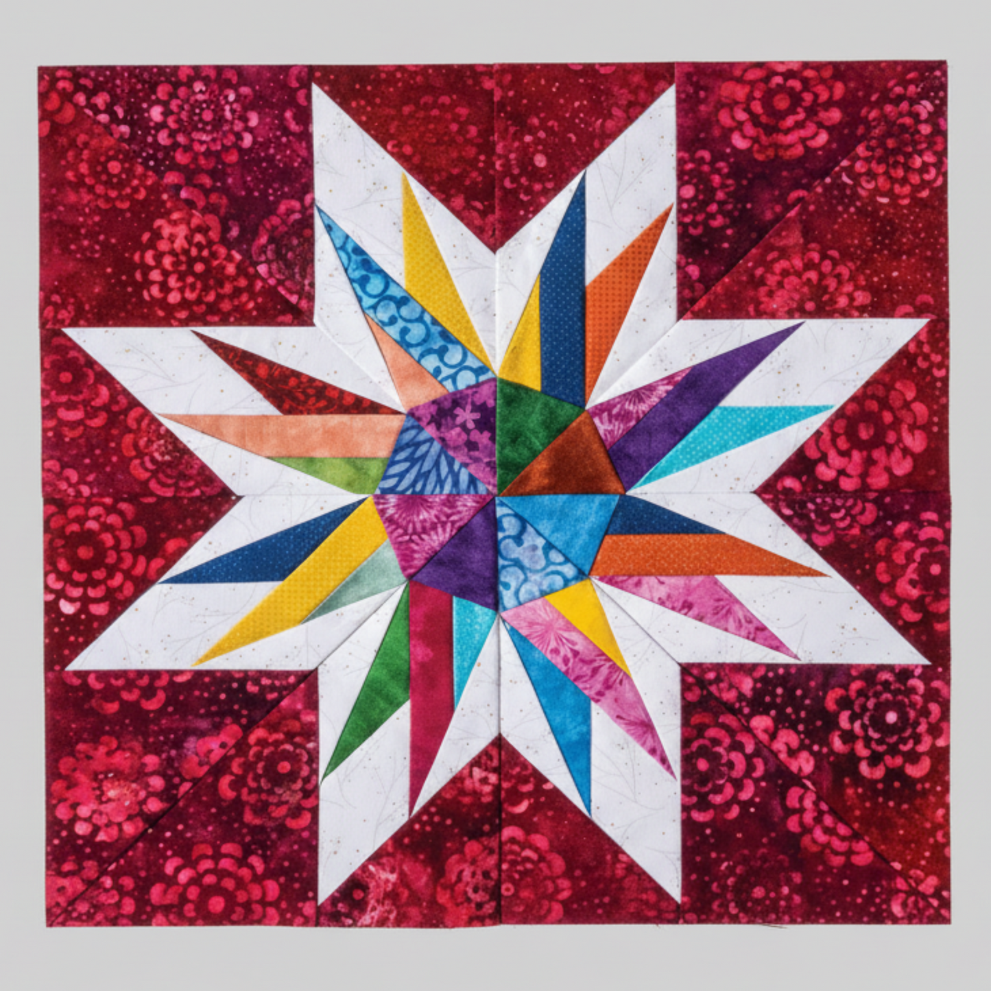 “Colorful paper-pieced star quilt block on red background from 60 Fabulous Paper-Pieced Stars book”