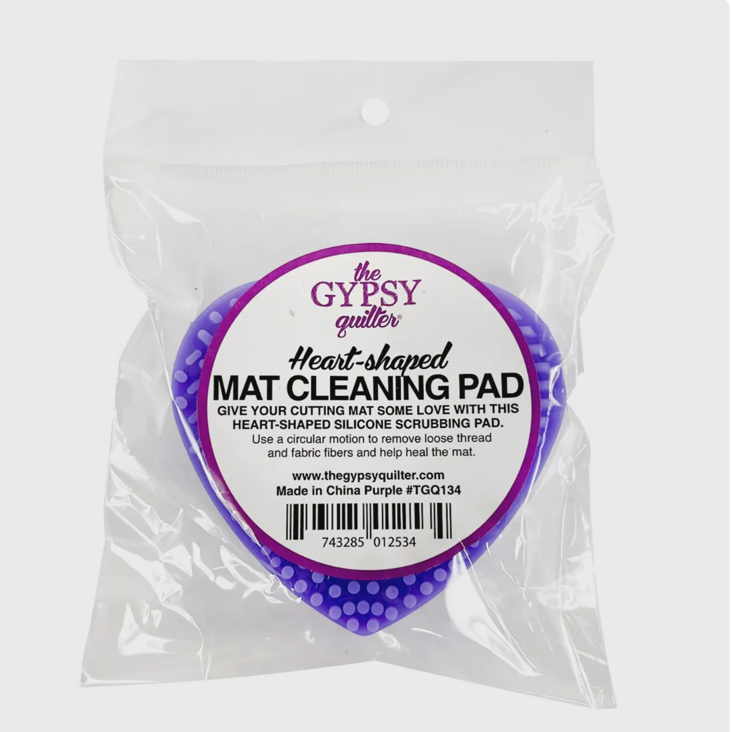 The Gypsy Quilter Heart-Shaped Cutting Mat Cleaning Pad in original packaging, purple silicone scrubber for cleaning self-healing cutting mats.