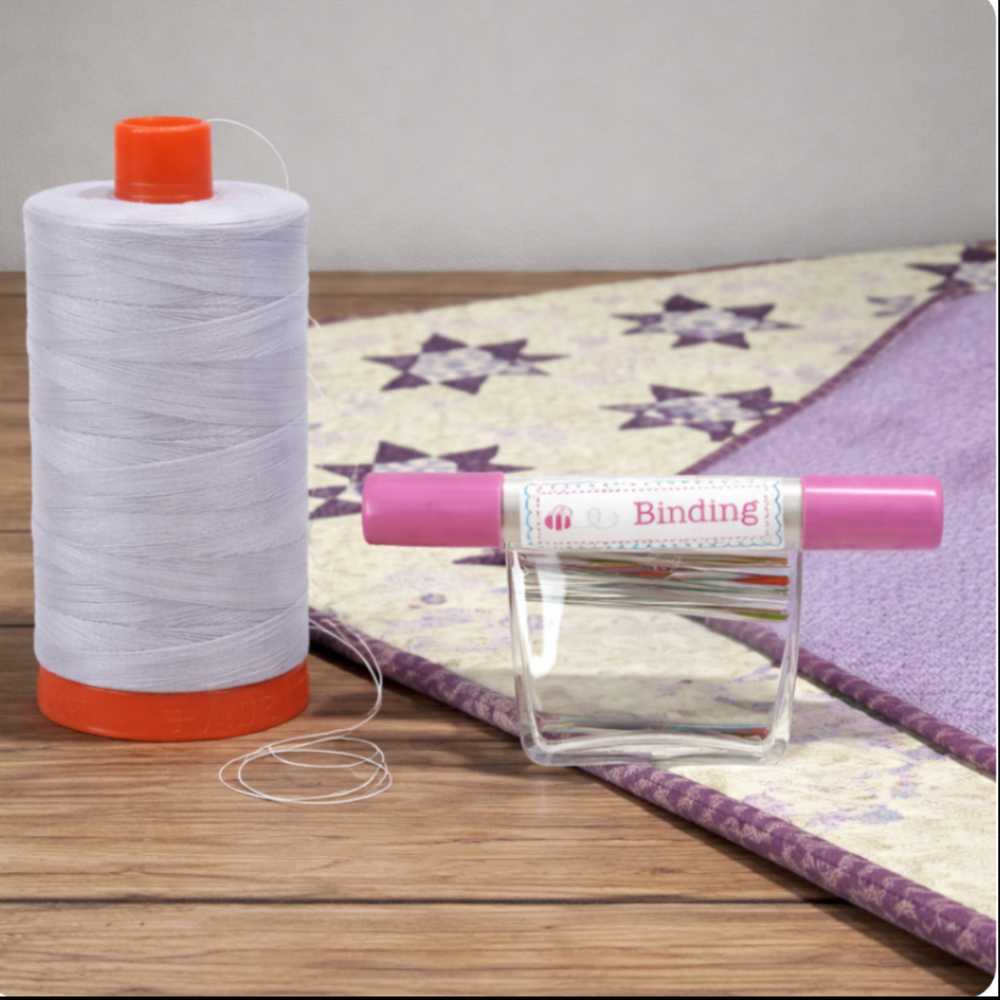 Aurifil Mako Cotton Thread 50wt Aluminum shown with binding needles and finished quilt project.