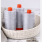 Three Aurifil Mako Cotton Thread 50wt Aluminum spools displayed in a woven basket with sewing accessories.