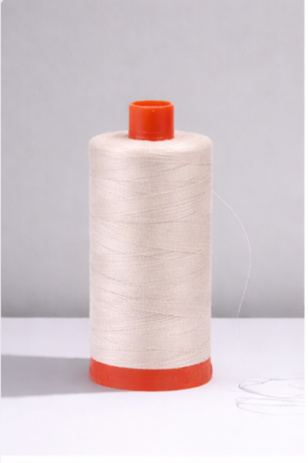 Aurifil Mako Cotton Thread 50wt in Aluminum, 1300-yard spool of long-staple Egyptian cotton on orange base.