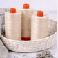 Three Aurifil Mako Cotton Thread 50wt Aluminum spools displayed in a woven basket with sewing accessories.