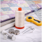 Aurifil Mako Cotton Thread 50wt Aluminum surrounded by rotary cutter, needles, and quilting tools.