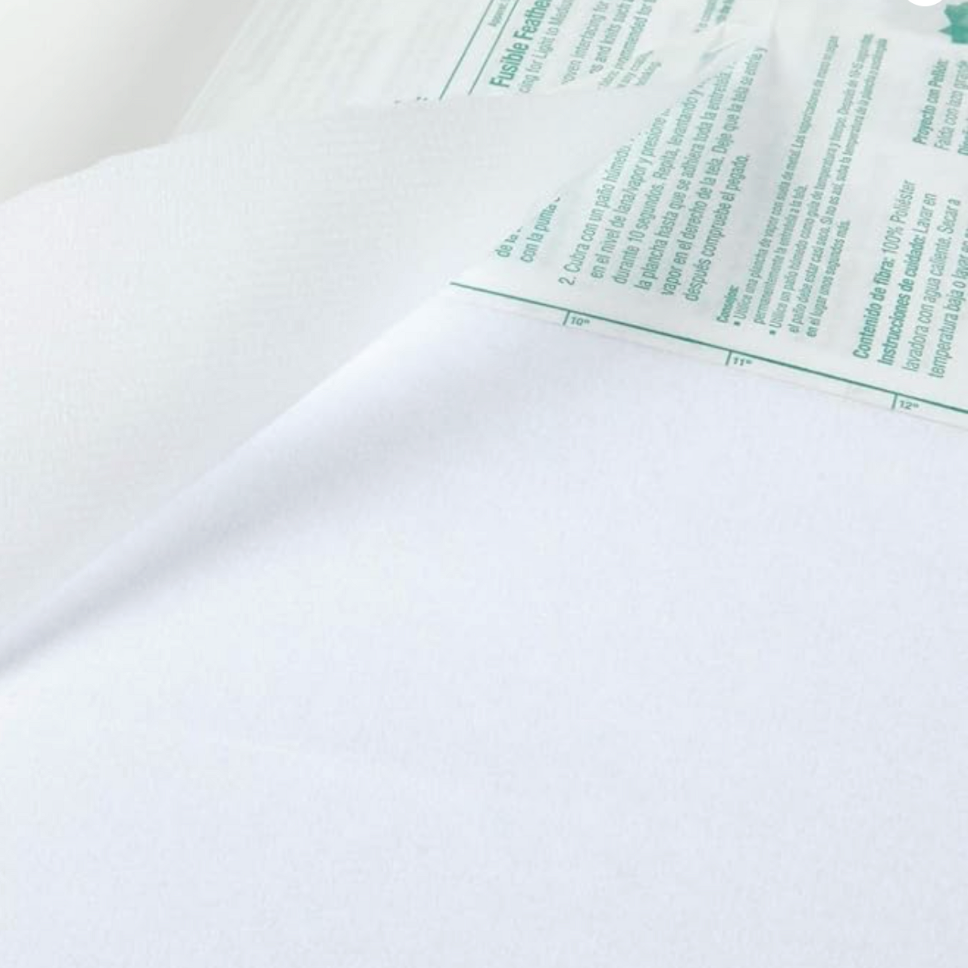 Close-up of a white Fusible Feather To Midweight  with green text of instruction  