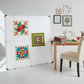 Quilting blocks  on a white design wall with a sewing table and chair in a room.