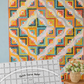Colorful curved quilt design displayed behind the Quick Curve Ruler, illustrating finished quilt results.