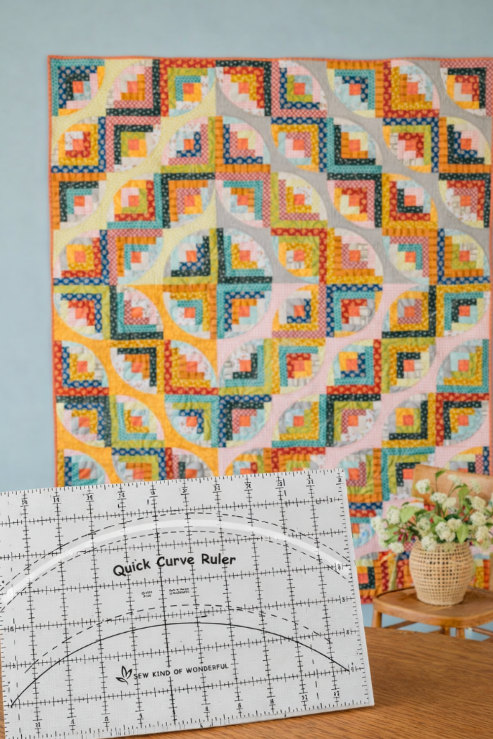 Colorful curved quilt design displayed behind the Quick Curve Ruler, illustrating finished quilt results.