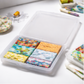 Colorful square tiles in a clear plastic container on a white surface with stationery items.