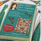 Book titled 'Kim Diehl's Best Applique Freezer Paper' on a table with sewing supplies.