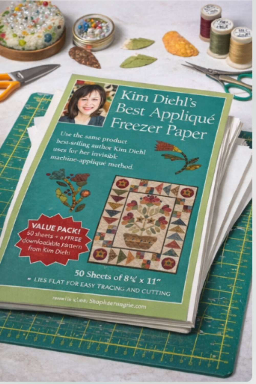 Book titled 'Kim Diehl's Best Applique Freezer Paper' on a table with sewing supplies.