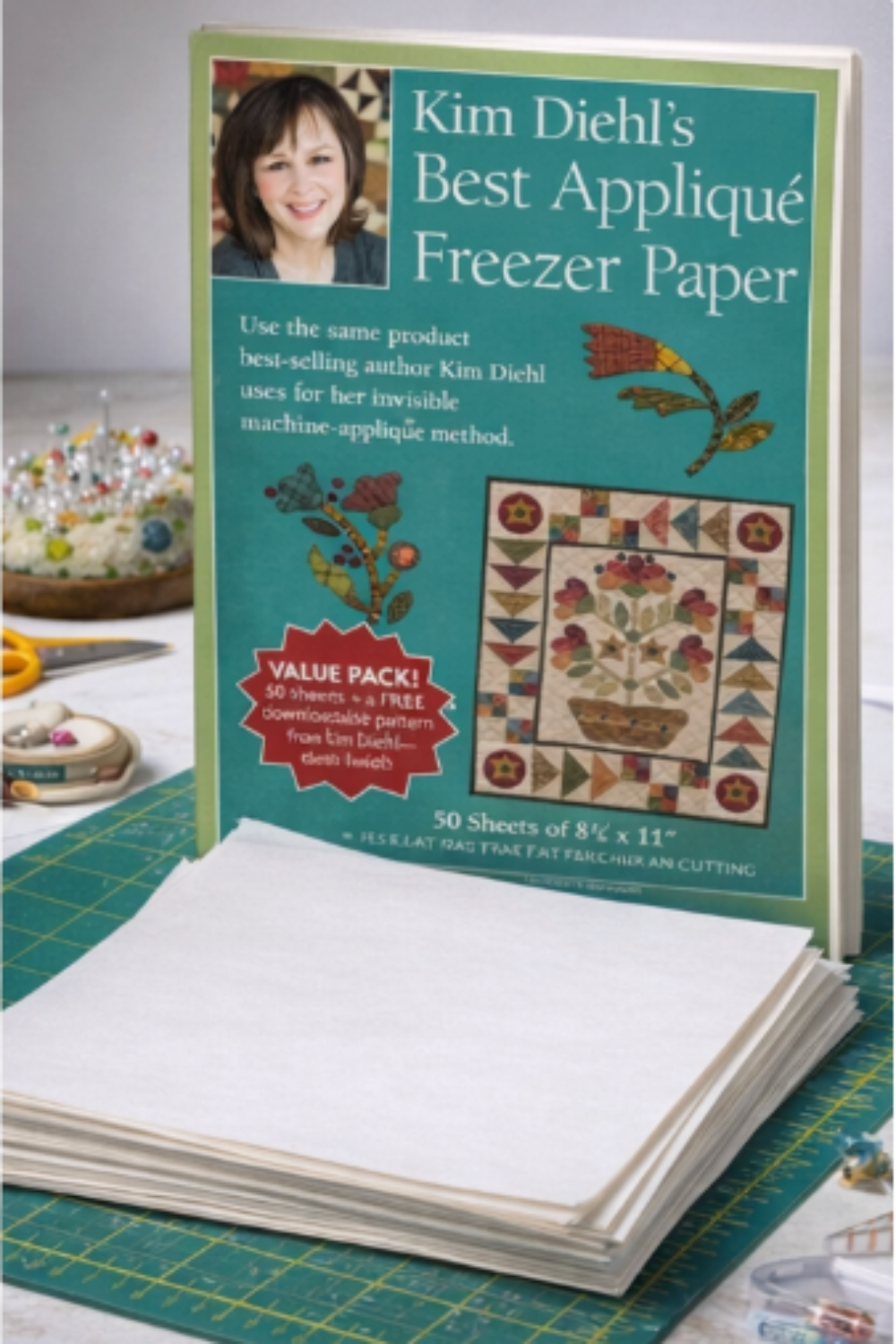Book titled 'Kim Diehl's Best Appliqué Freezer Paper' on a green cutting mat with appliqué materials.