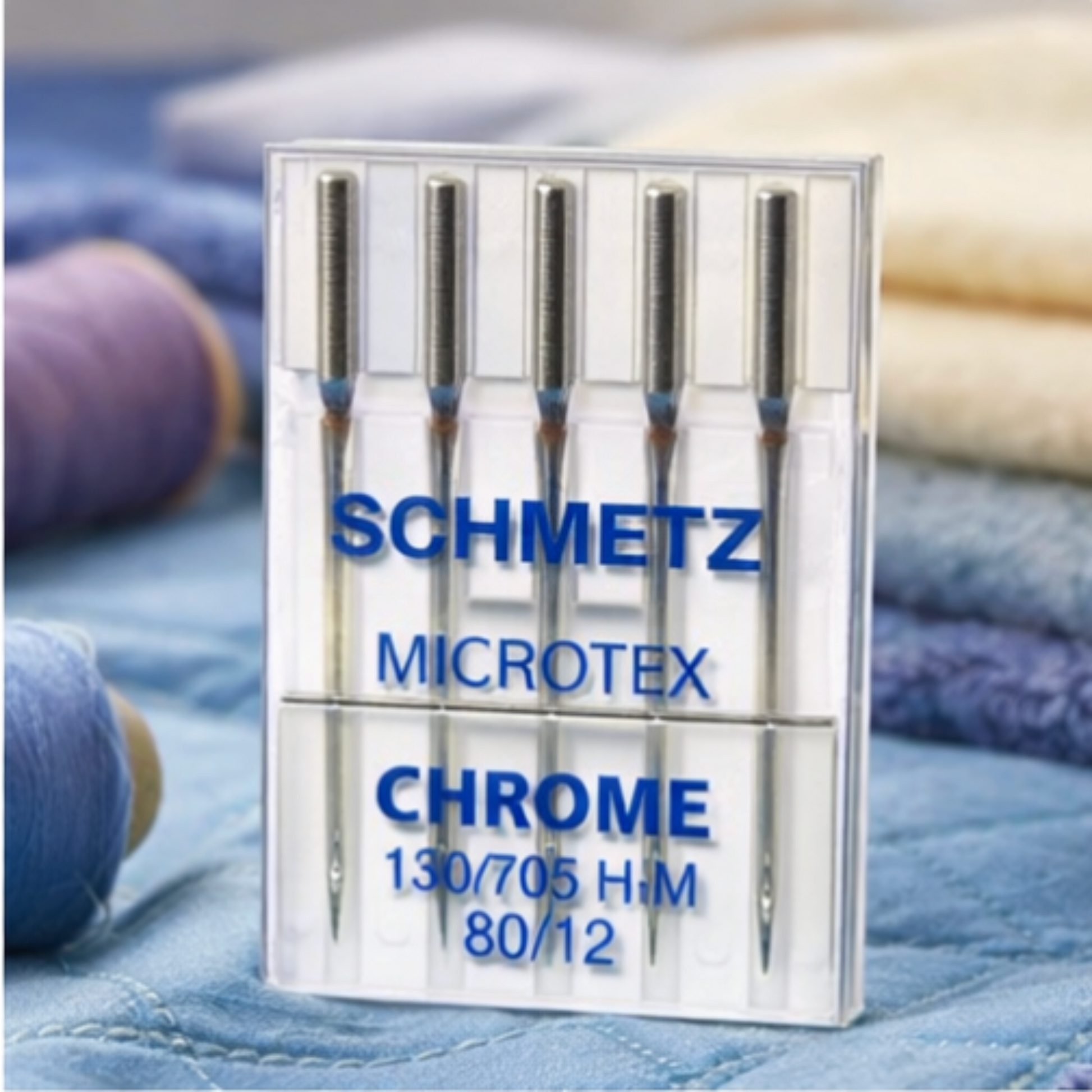 Pack of Schmetz Microtex Chrome needles on a fabric background
