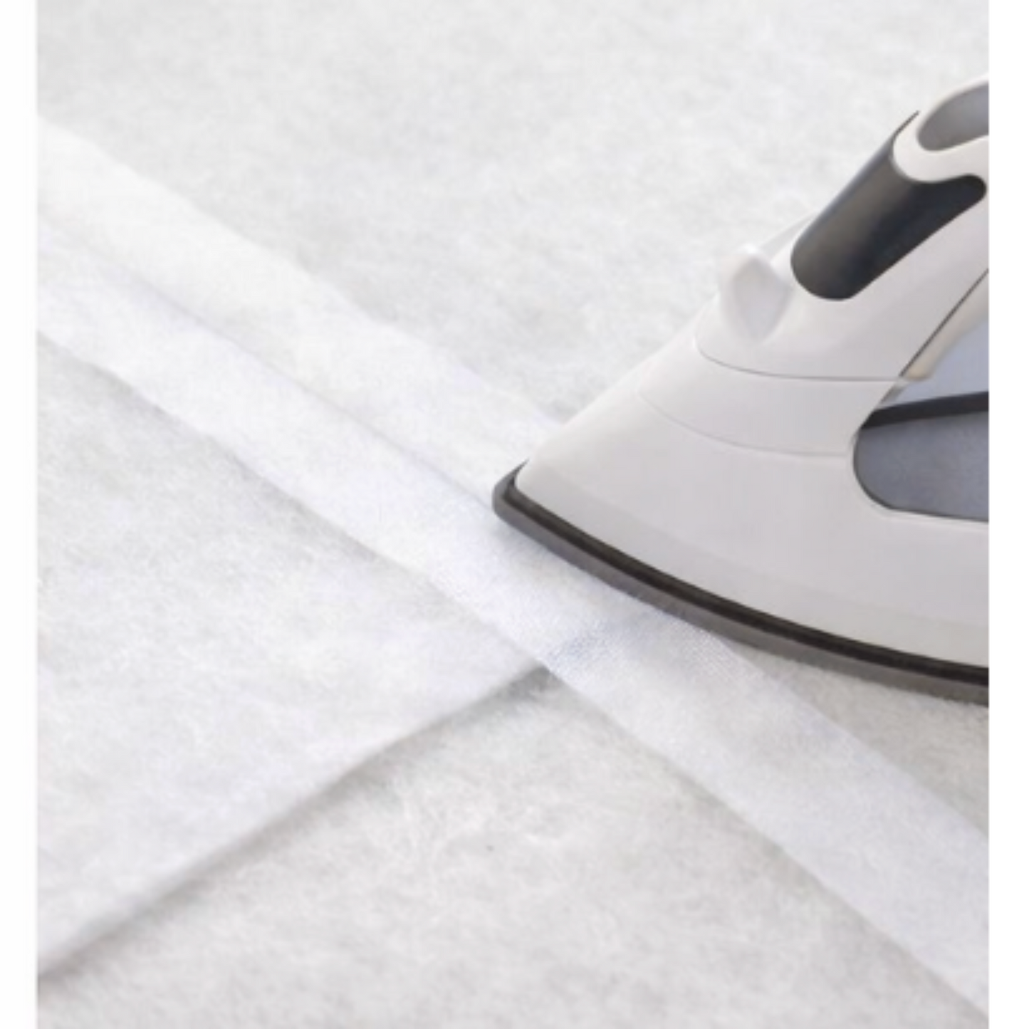 Fusible batting tape being ironed onto batting seam to join layers for quilting