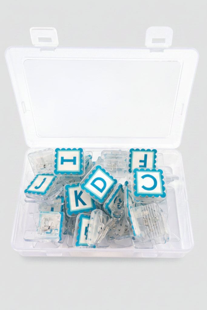 Open AlphaClippies storage case showing clear quilting clips with alphabet and number markers inside plastic organizer box