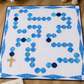 Rosary-inspired baby quilt displayed on nursery floor with teddy bear, woven basket, and inspirational Christian book