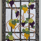 Grapevine quilted wall hanging with purple and golden grapes, green leaves, and black trellis border on a clean light background.