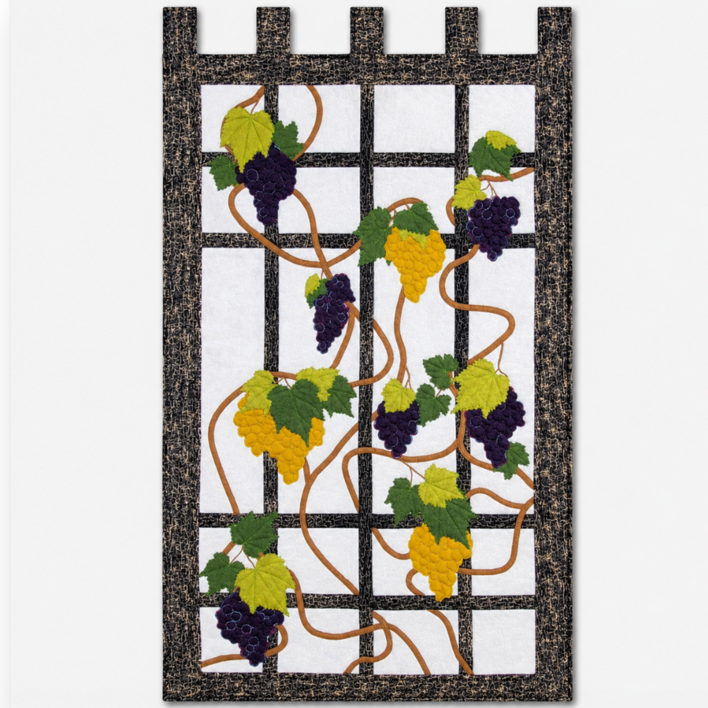 Grapevine quilted wall hanging with purple and golden grapes, green leaves, and black trellis border on a clean light background.