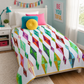 Colorful Diamond Daze handmade quilt draped on a teen girl's bed in a bright bedroom with white furniture, colorful pillows, and modern décor.