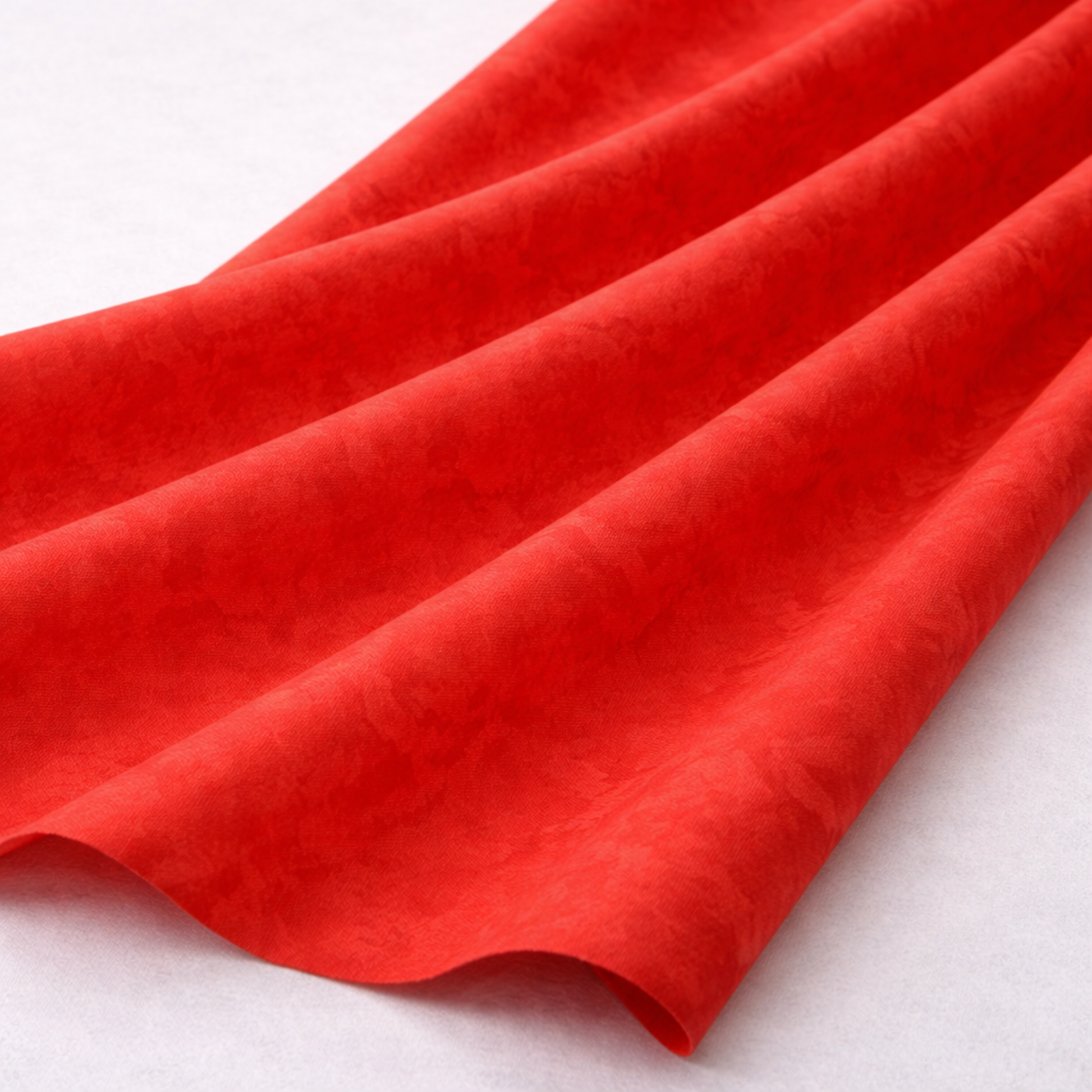 Expressions Batiks Hand-Dyes Tomato Red quilting cotton fabric by Riley Blake Designs draped in soft flowing folds on a white surface showing the organic painterly texture and subtle tonal variation of the bold vivid tomato red hand-dyed batik – 100% cotton batik, 43–44" wide