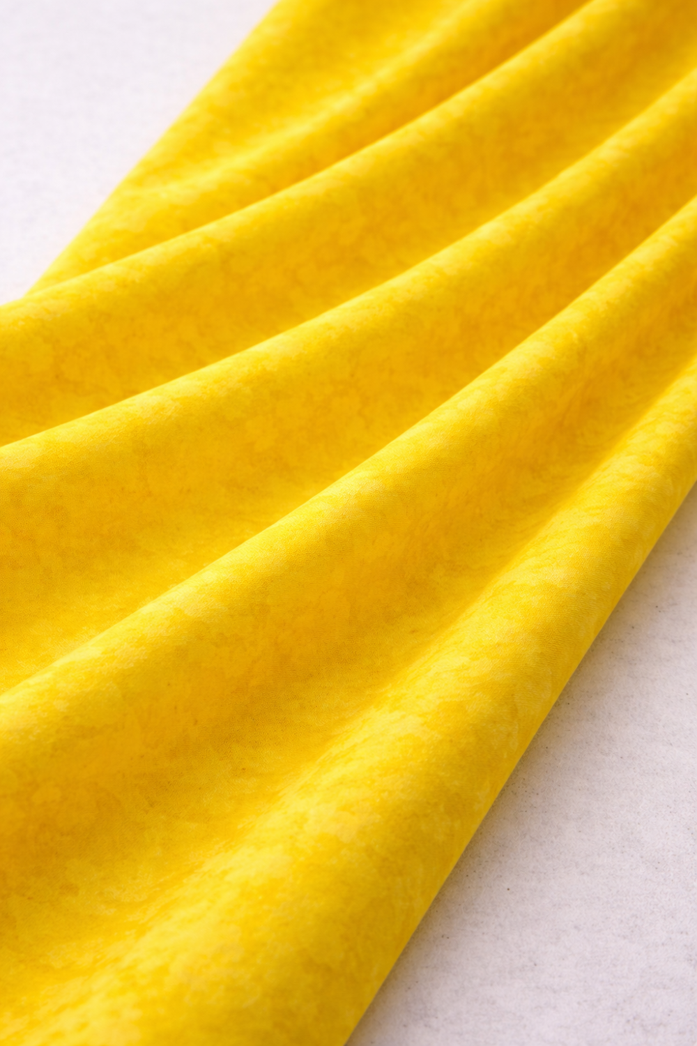 Expressions Batiks Hand-Dyed Bumblebee quilting cotton fabric by Riley Blake Designs – bright bumblebee yellow hand-dyed batik in soft folds on flat surface showing texture and tonal variation