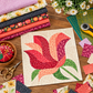 Colorful Superbloom fabrics styled with a Rose Garden quilt block inspired by the Sew Kind of Wonderful pattern on a sewing table with quilting notions.