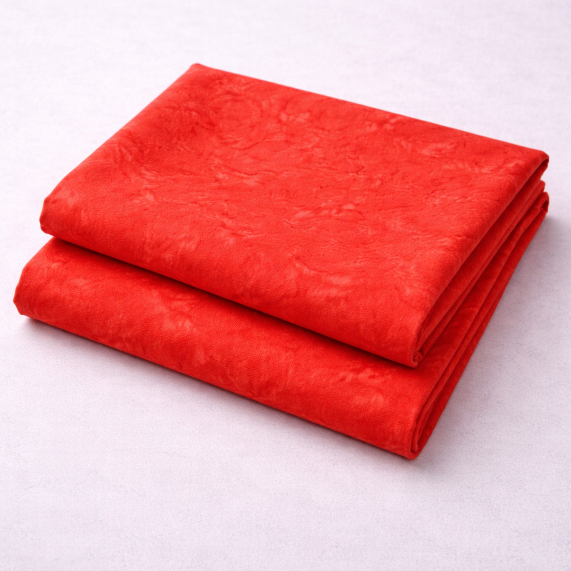 Expressions Batiks Hand-Dyes Tomato Red quilting cotton fabric by Riley Blake Designs folded in two neat stacked pieces on a white surface showing bold vivid tomato red tonal hand-dyed batik with subtle lighter rose highlights and deeper crimson organic mottled variation – 100% cotton batik, 43–44" wide