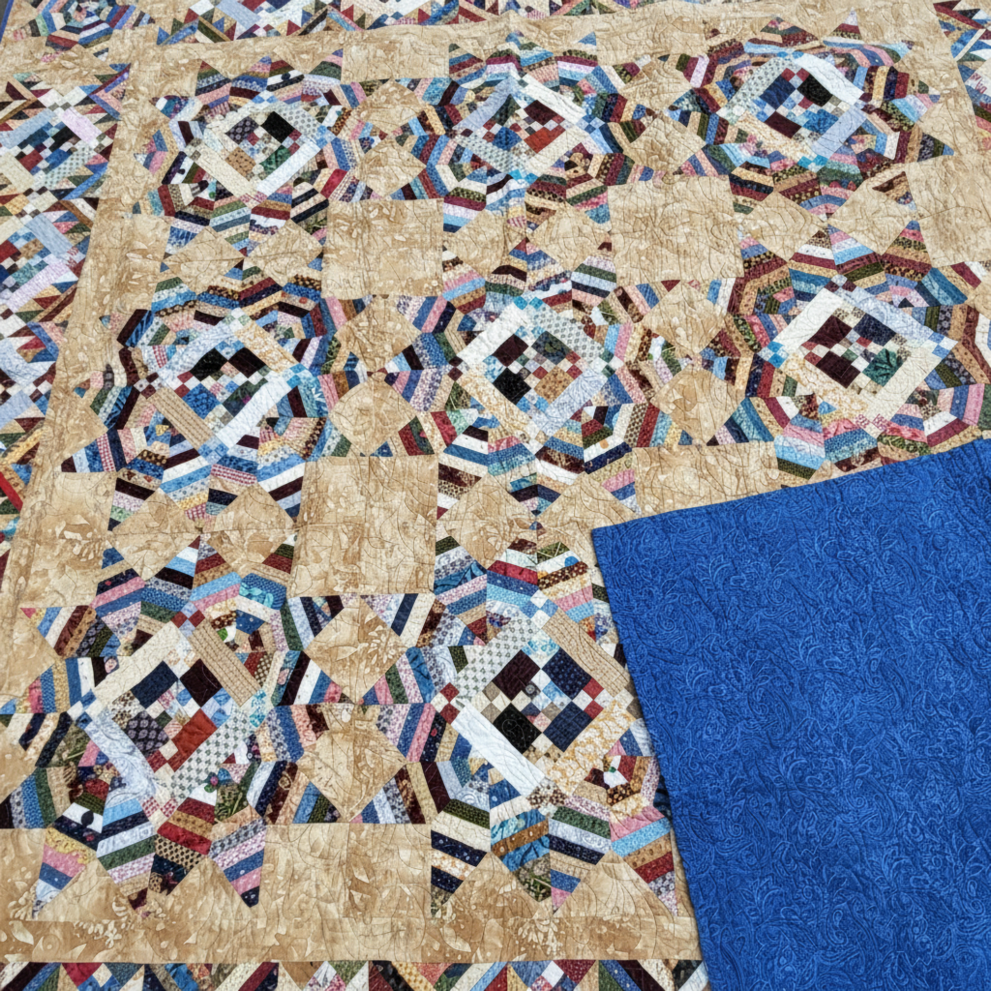 Trail Mix quilt showing scrappy patchwork front and solid blue quilt backing