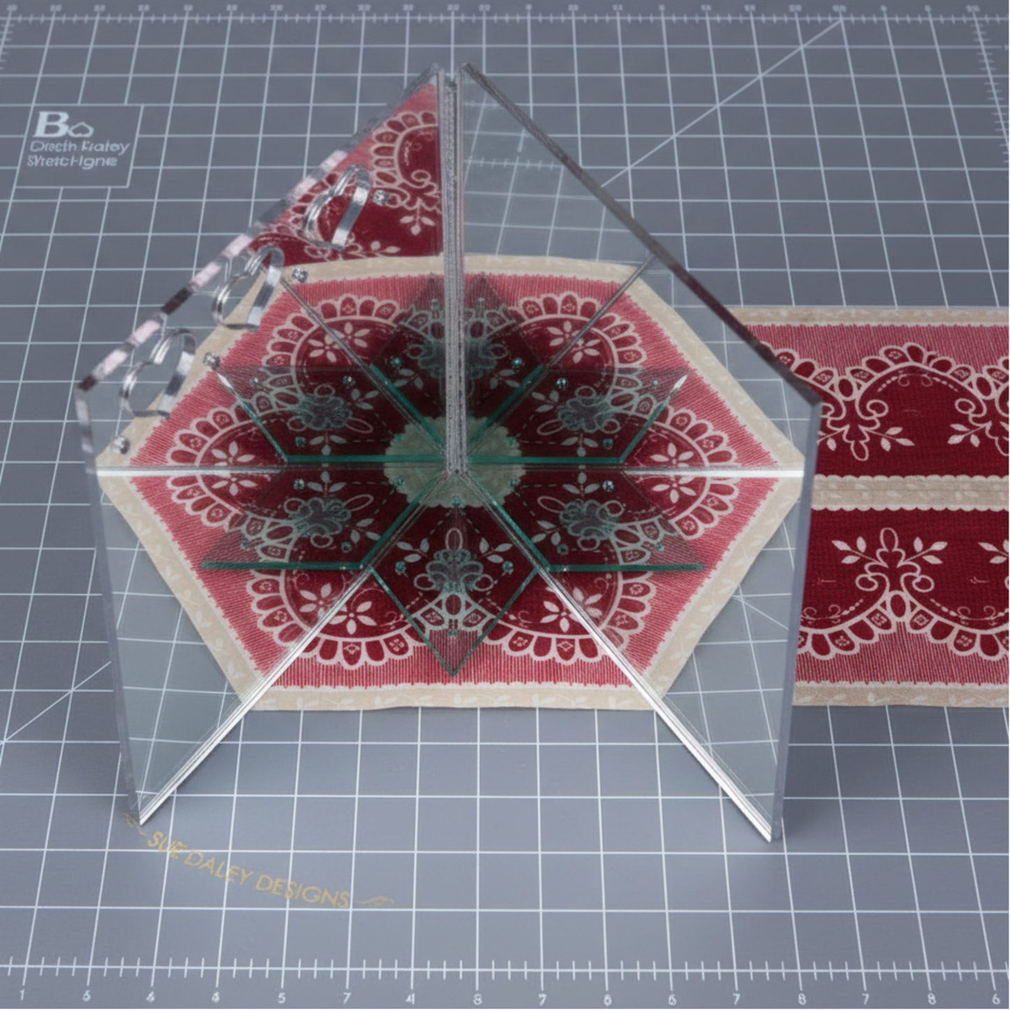 Sue Daley fussy cutting mirror demonstrating kaleidoscope fabric symmetry for quilting and English paper piecing