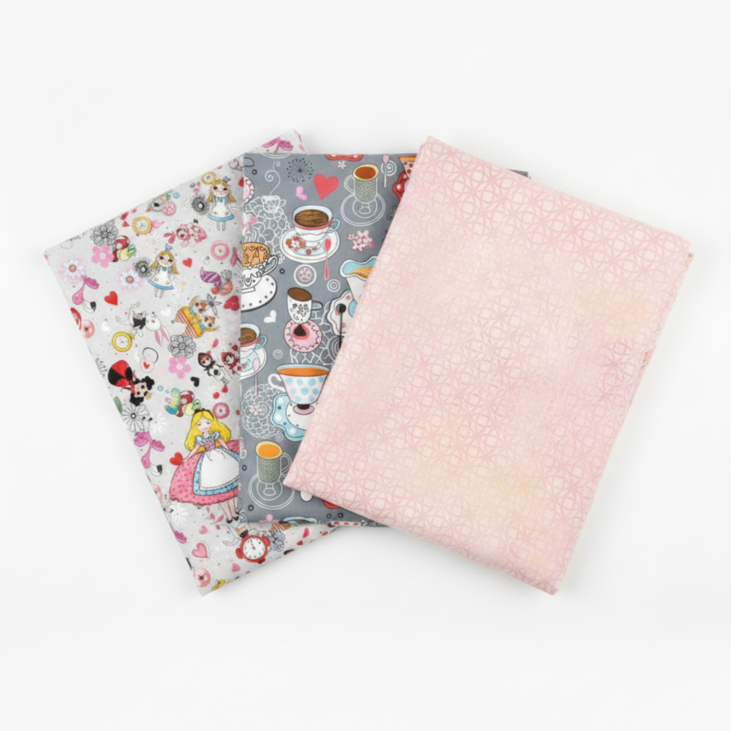 Alice Multi Characters, Alice Multi Teacups, and coordinating blush pink lattice quilting cotton fabrics by Jason Yenter for In The Beginning Fabrics shown in a three-fabric fan – whimsical Alice in Wonderland character scatter print, Mad Hatter teacup scatter print, and soft blush pink tonal geometric blender, 100% cotton, 3 yard cuts