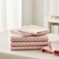Allure Peach Lattice fabric by Jason Yenter for In The Beginning Fabrics folded on a light cream linen surface with coordinating soft pink and peach fabrics – soft tonal geometric lattice in blush pink, peach, and cream, perfect as a background or blender for feminine quilt projects, 100% cotton, 3 yard cut