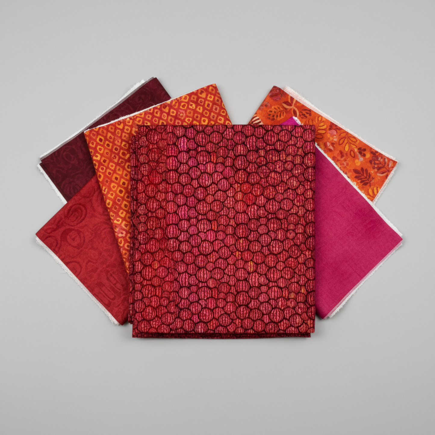 Allure Red Lanterns quilting cotton fabric by Jason Yenter for In The Beginning Fabrics shown in a coordinate stack with complementary warm-toned quilting fabrics in deep burgundy, crimson, magenta, and orange – allover striped oval lantern pattern, 100% cotton, 3 yard cut