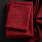 Allure Red Lanterns fabric by Jason Yenter for In The Beginning Fabrics folded on a dark surface with coordinating burgundy fabric – allover striped oval lantern pattern in rich crimson, ruby, and magenta, perfect for bold warm-toned quilt projects, 100% cotton, 3 yard cut