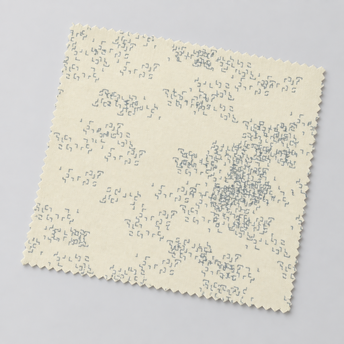 Angled swatch of Eggshell Edgy fabric by Zen Chic for Moda Fabrics on a light gray background, showing its subtle gray geometric print.