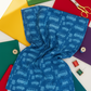 On the Go Automobiles Blue quilting cotton by Jason Yenter for In The Beginning Fabrics — vertical lifestyle flat lay with the cobalt-blue automobile print draped as the hero, surrounded by solid-color fabric folds in rainbow colors, thread spools, and gold scissors on a white surface. Coordinating fabrics and quilt patterns available at IraRobi Quilts.