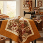 Interwoven Butterscotch Fabric by Jason Yenter for In The Beginning Fabrics as a wide quilted border and sashing in a framed autumn quilt draped over a vintage treadle sewing machine in a cozy sewing room. Quilt blocks shown for inspiration. Coordinating fabrics and quilt patterns are available at IraRobi Quilts.