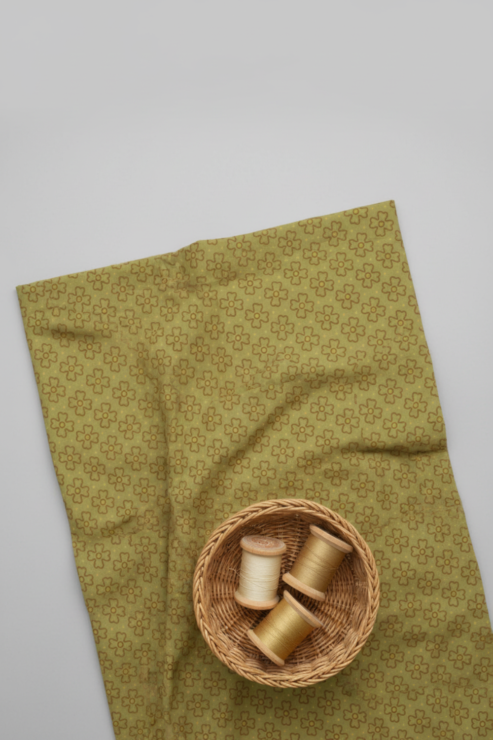 Golden Era Wavy Daisy Green by Paula Barnes for Marcus Fabrics — sage-olive green quilting cotton with wavy daisy motif styled with wicker basket and thread spools, 100% cotton — shop at IraRobi Quilts
