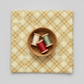 Golden Era Floral Plaid Tan quilting cotton by Paula Barnes for Marcus Fabrics — flat lay with wicker basket and thread bobbins in cream, red, and sage green, warm tan-gold ground with diagonal lattice and cream floral wreath motifs