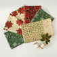 Winter Solstice II Beige Twigs Metallic Fabric by Jason Yenter for In The Beginning Fabrics — shown with coordinating quilting cottons fanned flat, with cream and gold metallic thread spools and a holly sprig. Coordinating fabrics and quilt patterns are available at IraRobi Quilts.