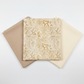 Three coordinating tonal blender fabrics in a fan arrangement featuring Expressions Batiks Breathe Ecru by Riley Blake Designs in warm cream with pine needle motif, flanked by soft warm taupe and ivory near-solid batiks – 100% cotton