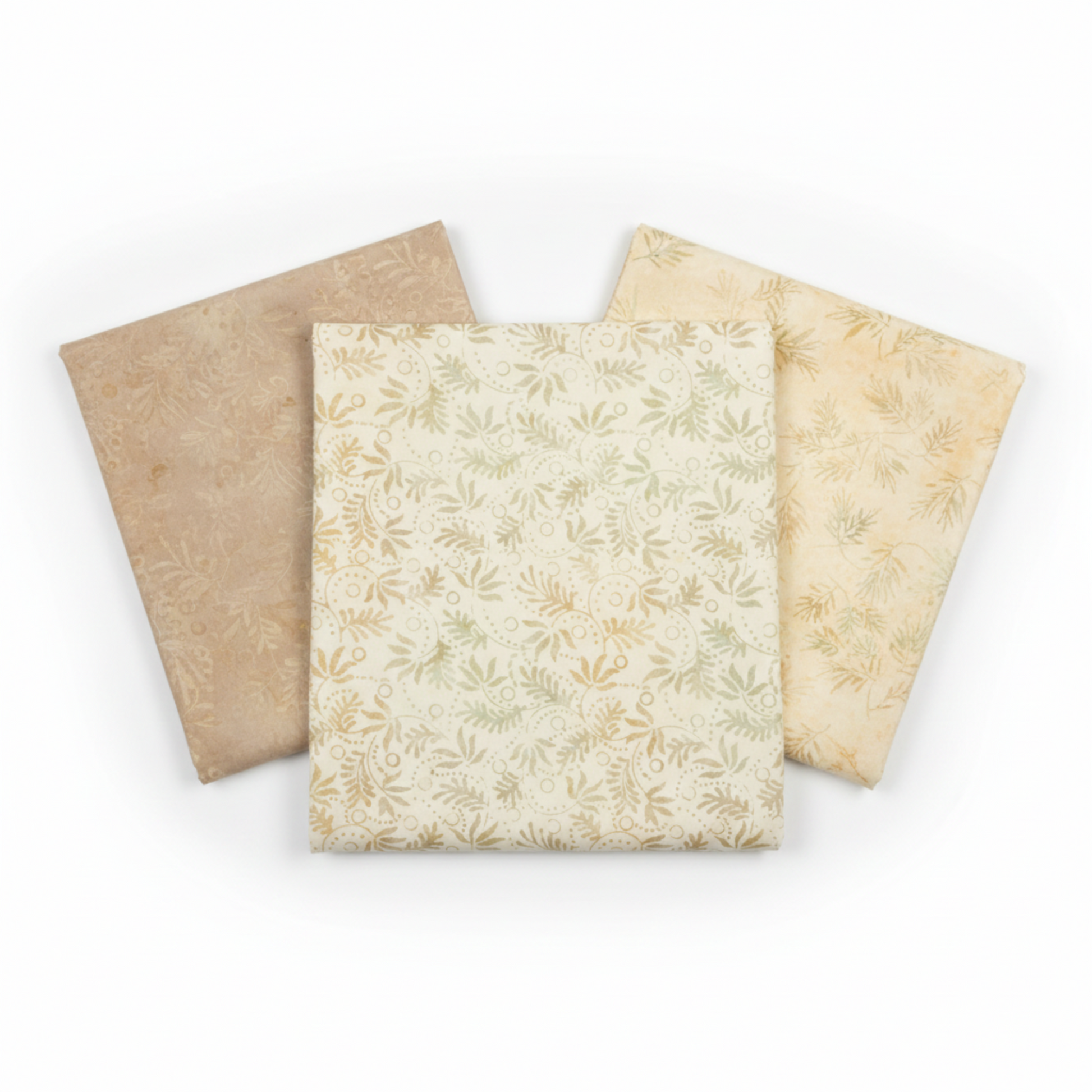 Three coordinating tonal batik fabrics in a fan arrangement featuring Expressions Batiks Breathe Laurel by Riley Blake Designs in cream and ivory with sage green leaf sprigs, flanked by warm taupe and soft golden-cream tonal batiks – 100% cotton