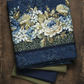 Carpet Bag Romance Blue Border Print fabric by Jason Yenter for In The Beginning Fabrics draped on a dark wood surface – lush cascading floral garland stripe with large ivory and blue roses, white hydrangeas, and olive foliage on deep navy damask ground, perfect for fussy-cut borders and vintage quilt projects, 100% cotton, 3 yard cut