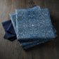 Carpet Bag Romance Blue Marble fabric by Jason Yenter for In The Beginning Fabrics folded on a dark linen surface – intricate symmetrical marbled damask with kaleidoscopic feathered medallion pattern in deep steel blue, slate, and navy with shimmering white highlights, perfect for vintage and antique-inspired quilt projects, 100% cotton, 3 yard cut