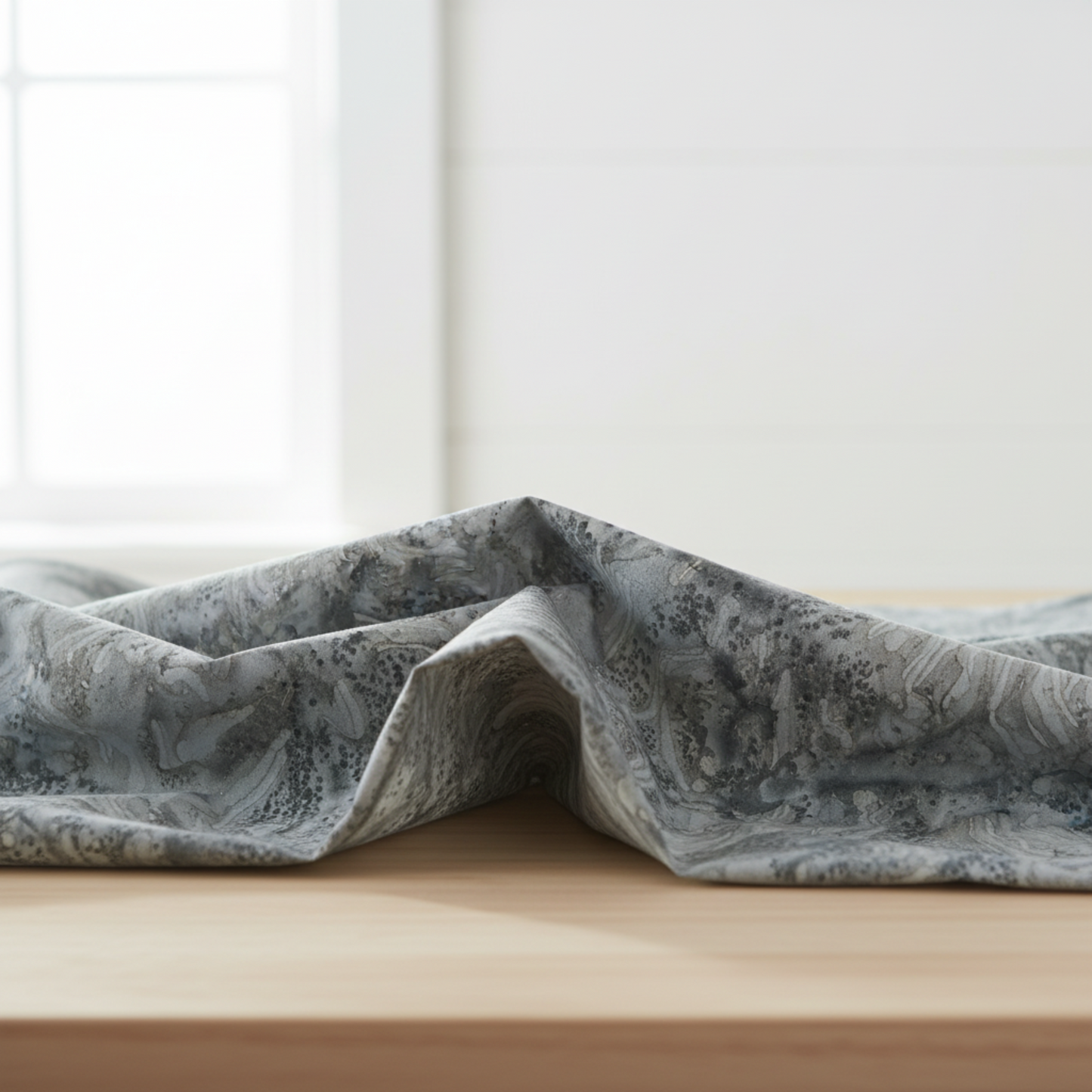 Expressions Batiks Hand-Dyes Charcoal quilting cotton draped over wood surface – deep gray hand-dyed batik blender by Riley Blake Designs with organic tonal swirl texture – available at IraRobi Quilts
