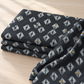 Folded Dance in Paris Lanterns Metallic Charcoal fabric on a light table, showing its gray lantern motifs and gold accents.