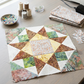 Unfinished star quilt block with a Coastal Path print center beside folded fabric, remnants, pins, thread spools, and a sewing machine. Quilt blocks shown for inspiration. Coordinating fabrics and quilt patterns are available at IraRobi Quilts.