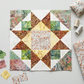 Unfinished star quilt block with a Coastal Path print center on a sewing table beside fabric remnants, thread spools, and a pincushion. Quilt blocks shown for inspiration. Coordinating fabrics and quilt patterns are available at IraRobi Quilts.