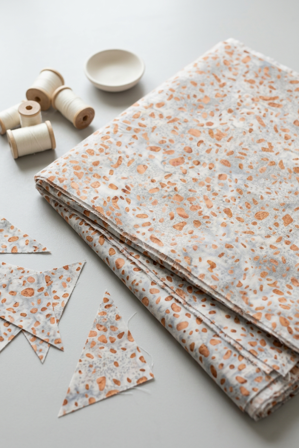 Terrazzo Coastal Path Fabric by Riley Blake Designs folded on a light-gray table beside matching triangular remn