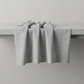 Essentials Connect The Dots Gray quilting cotton by Susan Winget for Wilmington Prints — fabric draped over a grey surface showing natural folds and raw cut edge, warm grey ground with tossed soft white scattered dots