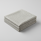 Essentials Connect The Dots Gray quilting cotton by Susan Winget for Wilmington Prints — three folded yards stacked on a grey surface, warm grey ground with tossed soft white irregular scattered dots