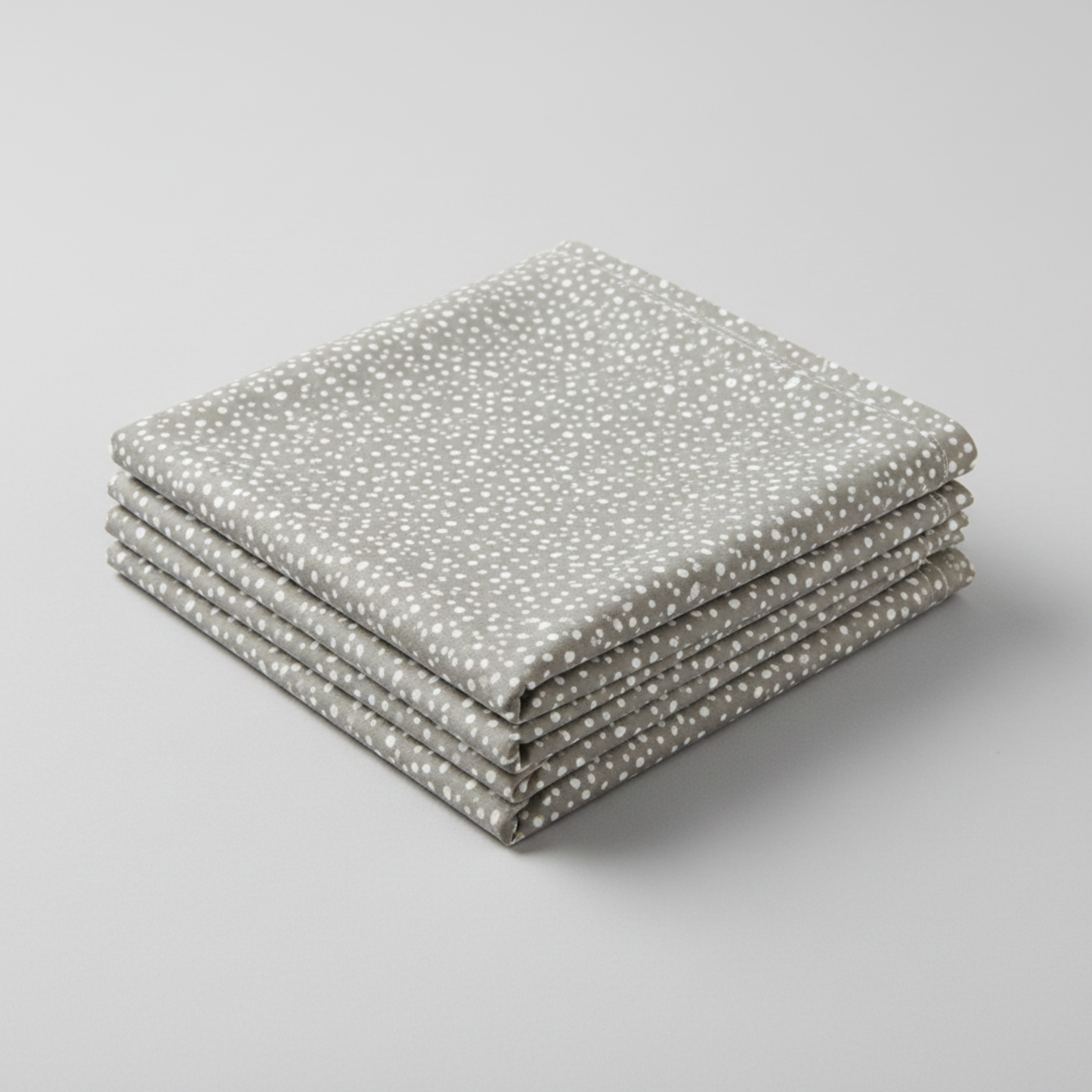 Essentials Connect The Dots Gray quilting cotton by Susan Winget for Wilmington Prints — three folded yards stacked on a grey surface, warm grey ground with tossed soft white irregular scattered dots